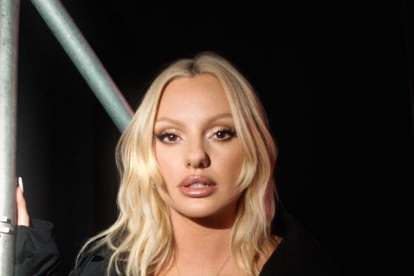 Alexandra Stan trista, imbracata in negru, avand in spatele ei un fundal intunecat si niste bare de metal