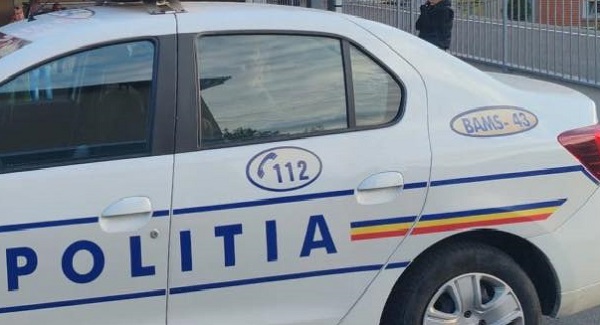 imagine prim-plan, masina de politie din Romania, stationata aproape de o poarta sau de un gard din metal
