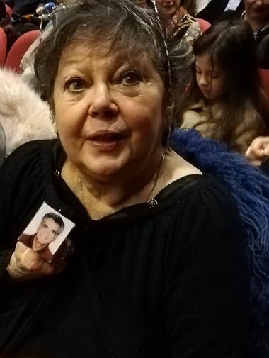 actrita Anca Pandrea in doliu, având agatata in piept o poza cu Iurie Darie, stand pe scaun intr-o sala de teatru cu spectatori