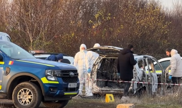 masina de politie, criminalisti si anchetatori aflati langa perimetrul izolat in care a fost gasit un autoturism alb carbonizat pe un drum din preajma unui camp de la marginea Oradei