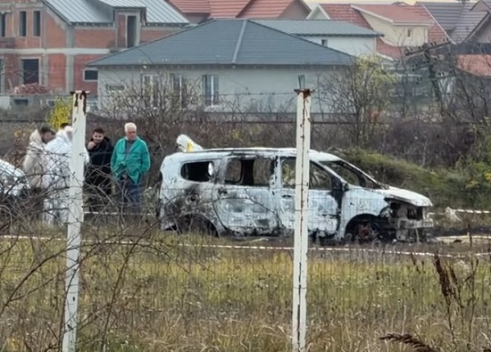 criminalisti, anchetatori si martori care stau langa o masina alba arsa gasita pe un camp intr-o zona de la marginea Oradei