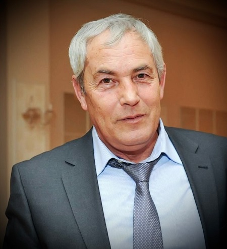 Fostul jucător de rugby si antrenor Virgil Balasa, imbracat in sacou gri, camasa bleu si cravata gri, stand intr-un cadru interior 