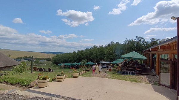 imagine de la complexul turistic Ferma Dacilor din satul Tohani, judetul Prahova, imagine cu terasa restaurantului si cu vizitatori care se plimba