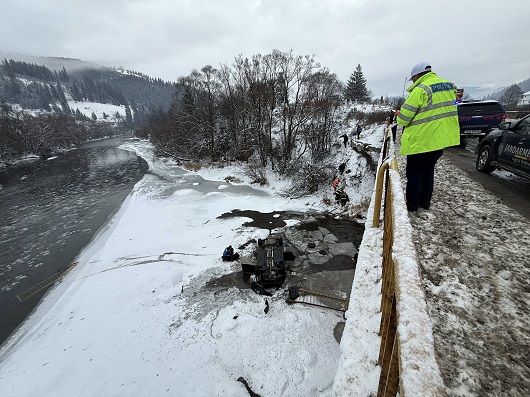 imagine de la locul accidentului rutier de la Vatra Dornei de pe 6 ianuarie 2026, politist cu vesta reflectorizanta privind peste parapet autoturismul rasturnat pe gheata de pe raul Bistrita, masini de politie si ale jandarmeriei incercand sa intervina 
