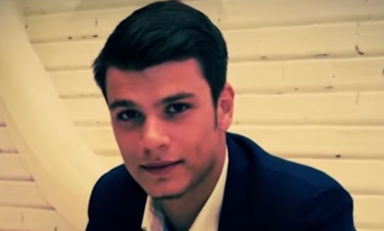 Mario Iorgulescu acum cativa ani, imbracat cu camasa alba si sacou bleumarin, stand cu spatele la un perete alb