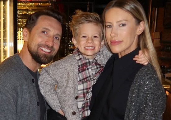 Dani Oțil vesel, imbracat cu pulover gri, alaturi de fiul lui, Tiago, imbracat cu camasa in carouri rosii si gri si pulover gri si de sotia lui, Gabriela Prisacariu, imbracata cu camasa neagra si pulover gri inchis, toti trei aflandu-se intr-un restaurant