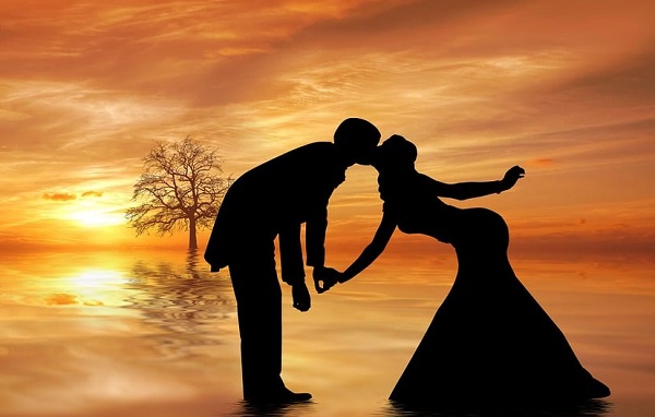 ilustratie generata AI, siluete negre ale unor parteneri de cuplu, atat partenera, cat si partenerul aplecandu-se ca sa se sarute intr-un colt de natura cu copaci, la apus de soare