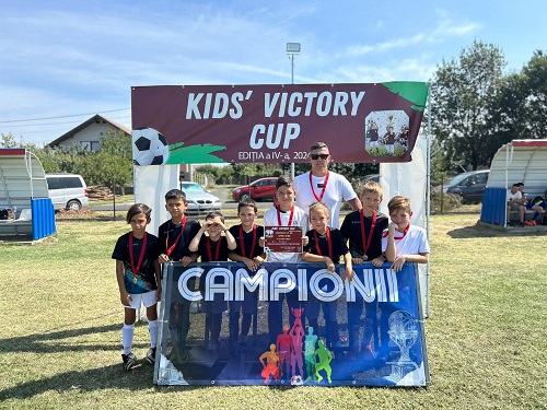 echipa de fotbal formata din copii din cadrul clubului AS Bobda stand pe teren cu antrenorul lor dupa ce au primit medalii pentru ca au fost castigatorii unei competitii de fotbal  