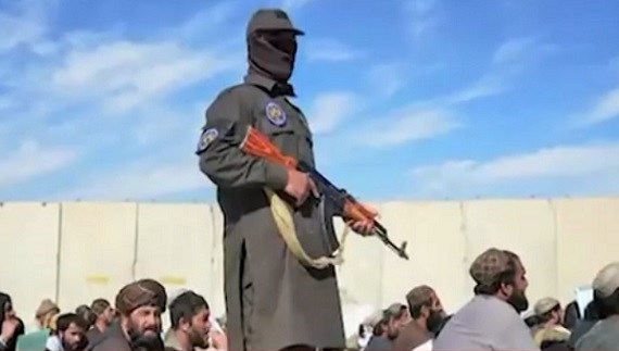 captura video, reprezentant al forțelor de ordine din Afganistan, tinand in mana o pusca in timp ce supravegheaza un grup de barbati care isi spun rugaciunea in aer liber