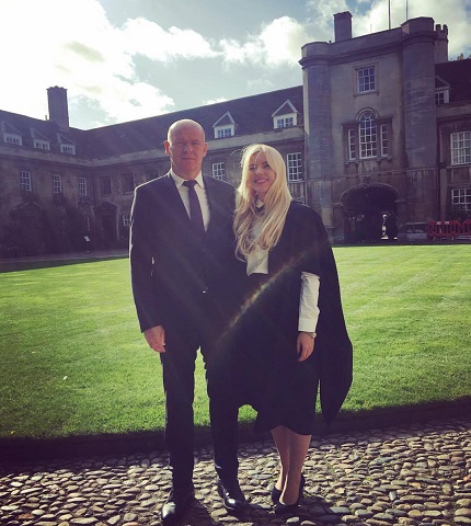 Karina Paval imbracata cu camasa alba, fusta neagra si roba, fericita alaturi de tatal ei, Dragos Paval, imbracat cu costum negru, camasa alba si cravata, in timp ce stau in curtea Universitatii Cambridge din Marea Britanie