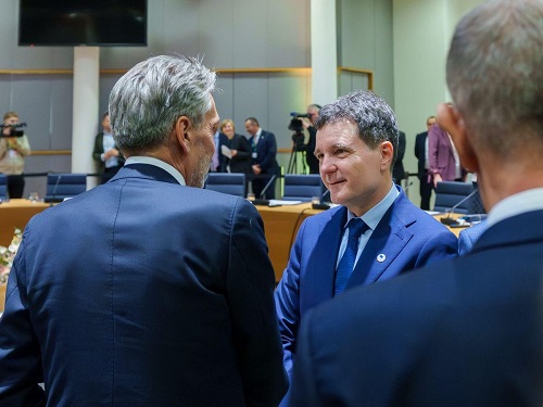 președintele Rom&acirc;niei Nicușor Dan imbracat cu costum albastru, camasa bleu si cravata albastra stand de vorba intr-o sala de conferinte cu doi participanti la o reuniune la care a fost prezent mai demult