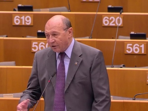 fostul presedinte Traian Băsescu imbracat in costum violet, cu camasa lila si cravata violet, stand in picioare in tribune la Parlamentul European si vorbind la microfon in cadrul unei interventii