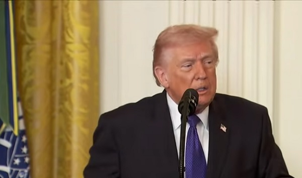 președintele SUA Donald Trump imbracat in sacou negru, avand camasa alba si cravata albastra, in timp ce vorbeste la microfon la pupitru in timpul unei conferite de la Casa Alba