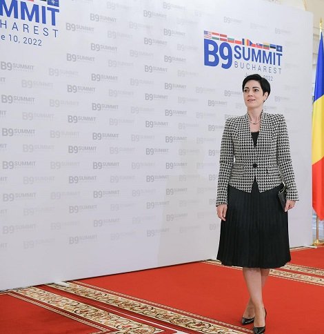 consilierul prezidential Delia Dinu, imbracata in sacou alb cu negru si fusta neagra plisata la Summitul B9 de la București din anul 2022 