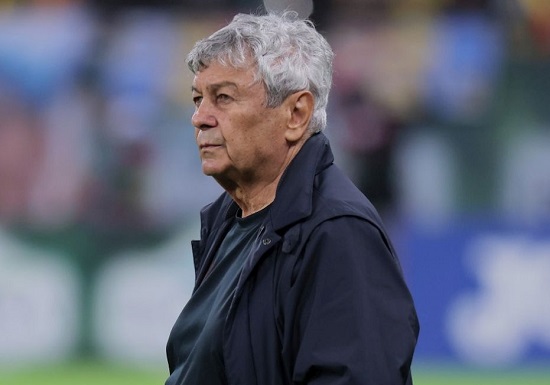 Mircea Lucescu ganditor, imbracat in bleumarin, in timp ce se afla pe un teren de fotbal