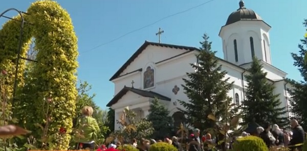 imagine din curtea Mănăstirii Ghighiu din județul Prahova intr-o zi insorita, in curte observandu-se mai multi credincioși