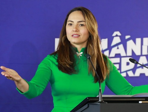 Anamaria Gavrila imbracata cu rochie verde, gesticuland cu bratele in timp ce se afla in fata unui pupitru negru cu microfon si tine un discurs in cadrul POT
