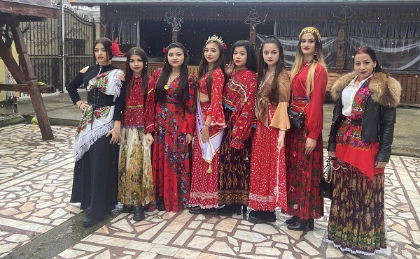 Garoafa, femeia de 42 de ani cu 4 clase din Potcoava, Olt, imbracata cu jacheta neagra de piele cu guler de blana, cu fusta traditionala rromani, stand alaturi de cateva fete imbracate in port traditional rromani, in curtea unei case
