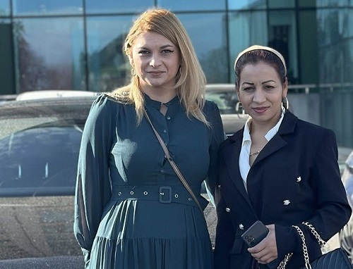 Stela Garoafa, femeia cu 4 clase din Potcoava, judetul Olt, care viseaza sa-si dea Bacul,imbracata cu bluza alba și sacou bleumarin, tinand intr-o mana telefonul si geanta cu lant auriu, in timp ce se afla langa o alta femeie,imbracata cu rochie lunga verde, amandoua stand langa o masina neagra in fata unei cladiri cu peretii de sticla
