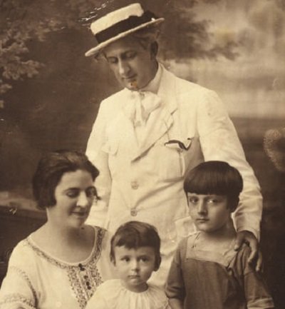 fotografie alb-negru, Dinu Lipatti in copilarie, alaturi de mama sa, Ana Lipatti, imbracata in ie, de fratele sau mai mic, aflat in bratele mamei si de tatal lor, Theodor Lipatti, imbracat cu costum alb si purtand pe cap palarie