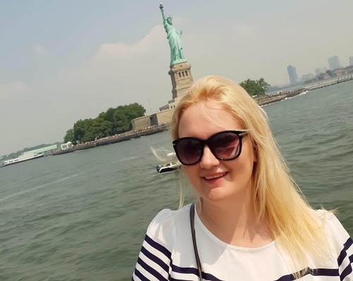 Diana Postică, soția premierului desemnat Eugen Tomac, imbracata cu bluza alba cu dungi negre, purtand ochelari negri de soare, in timp ce se afla pe un vas de promenada la New York, in spatele ei fiind Statuia Libertatii si zgarie-nori 