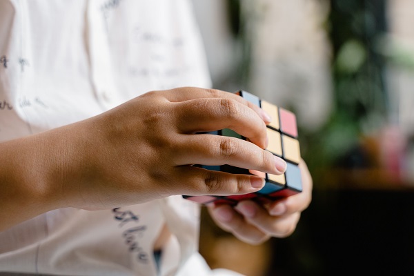 baietel imbracat cu tricou alb cu scris negru, incercand sa lucreze cu un cub Rubik