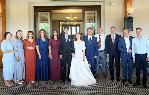 Eliana, fiica cea mare a sotilor Bodnariu, in rochie de mireasa, alaturi de sotul ei, David, imbracat cu costum de culoare inchisa si de o parte dintre invitatii la nunta lor in fata complexului la care s-a organizat petrecerea de dupa nunta
