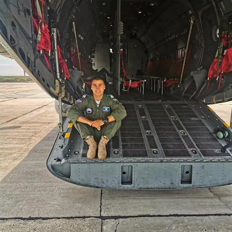 pilotul militar Mihai Vîrdol de la Baza 90, imbracat in uniforma, zambitor, stand asezat pe scarile de la intrarea intr-o aeronava militara aflata pe pista