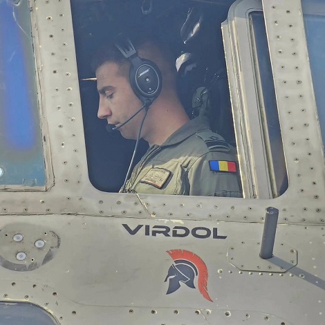pilotul militar Mihai Vîrdol in uniform, avand casti la urechi, in timp ce se afla la bordul unei aeronave militare pe care scrie numele sau