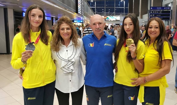 Ștefania Uță, multiplă campioană la proba de 400 metri garduri, imbracata in tricou galben, aratandu-si mandra medalia de aur alaturi de alte sportive si de antrenorii lor pe aeroport dupa ce s-au intors de la o competitie importanta