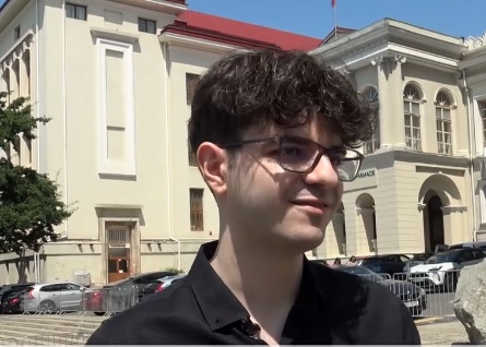captura video, Calin Vamesu, tanarul care a absolvit Facultatea de Medicina din Iasi cu media 10, zambitor, purtand ochelari si camasa neagra, in timp ce acorda un interviu in aer liber, langa UMF Iasi