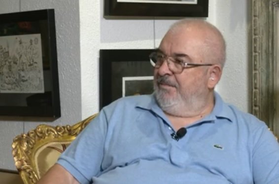 captura video YouTube, regizorul si actorul Gelu Colceag,purtand ochelari, imbracat cu tricou bleu, avand in spatele sau un perete plin de tablouri, in timp ce sta pe un scaun vintage auriu si da un interviu