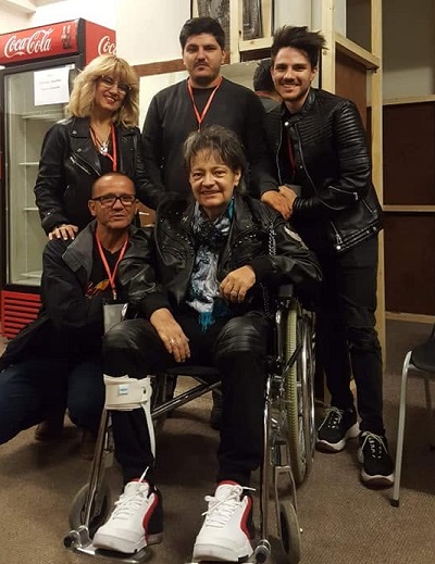Leo Iorga imbracat in negru, cu pantaloni de piele, avand orteza la picior, in scaun cu rotile, avandu-i alaturi de pe sotia lui, Paula, pe cei doi fii ai lor si pe un barbat de culoare, la ultima sa aparitie pe scena, in anul 2019