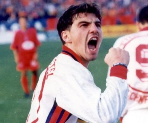 Catalin Hîldan, imbracat cu echipament sportiv al clubului Dinamo, in alb si rosu, incordandu-si pumnul si strigand in timp ce se afla pe teren intr-un meci
