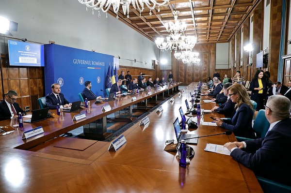 imagine din sala in care a avut loc prima ședință de Guvern a Cabinetului lui Luca Niculescu, toți miniștrii stand la o masa mare, cu microfoane si laptopuri in fata