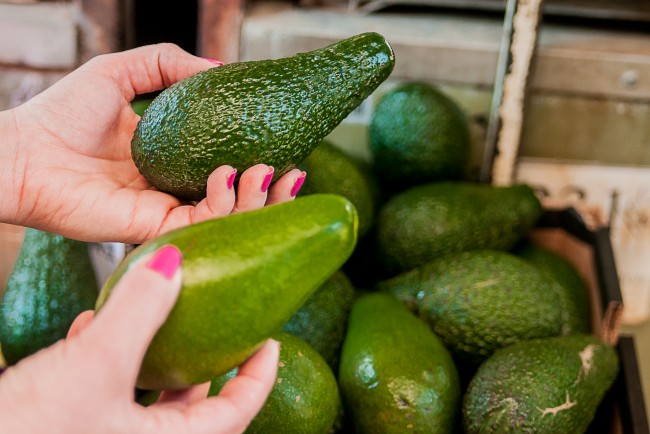 Client care alege dintre 2 bucati de avocado in supermarket