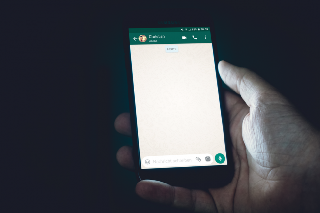 Persoana care tine smartphone in mana si scrie pe WhatsApp