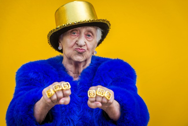 Femeie în vârstă amuzantă și extravagantă care pozează pe fundal colorat