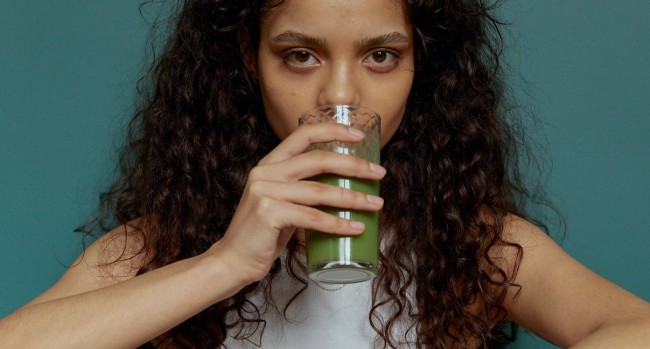 Femeie creola care bea un smoothie verde