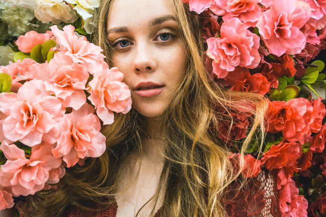 Fata blonda, portret aproape, inconjurata de flori roz
