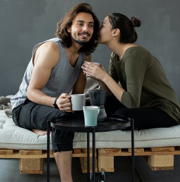 cuplu care discuta pe canapea alaturi de cani de cafea