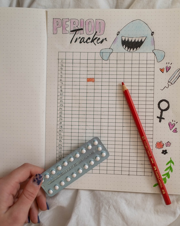 calendar menstrual cu semne amuzante si mana de femeie cu pastile anticonceptiomale