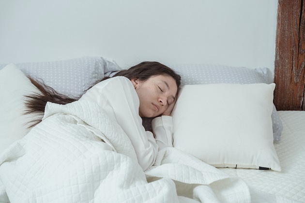 fată care doarme într-un pat cu așternut alb 