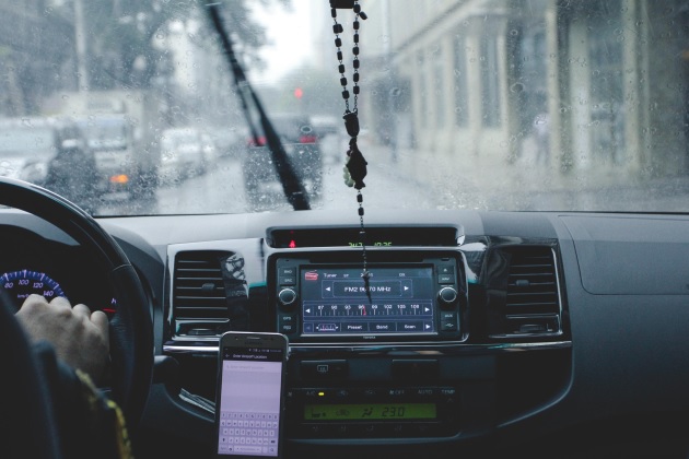 bordul unei mașini, telefon prins într-un suport, radio-ul pornit