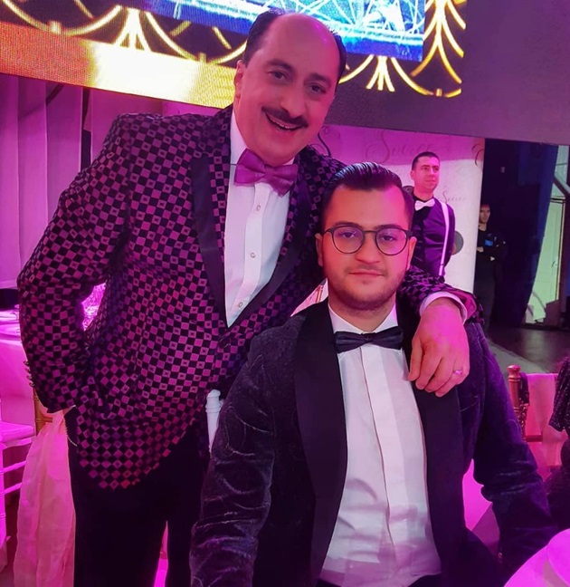Romică și Cătălin Țociu, îmbrăcați la costum și papion într-o sală de evenimente