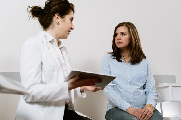 Pacientă si medic stând de vorbă în timpul unei consultații într-un cabinet medical