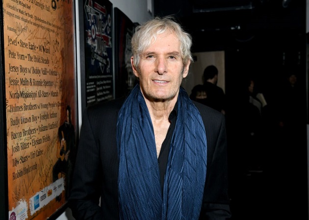 Michael Bolton în cadrul unui eveniment public, îmbărcat într-o haina neagră și o esarfă albastră la gât 