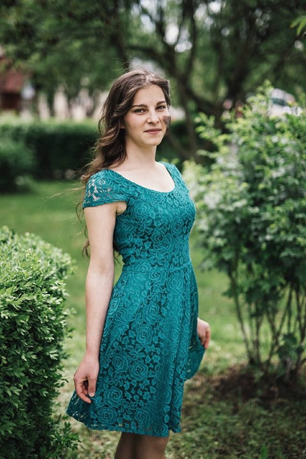 Maria Banciu într-un parc, tinându-și cu mâna colțurile rochiței sale de culoare cobalt