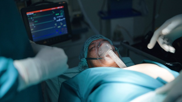 Persoană intubată într-un pat de spital, sub supravegherea a doi medici