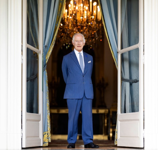 Regele Charles al III-lea îmbrăcat într-un costum albastru, în balconul palatului buckingham